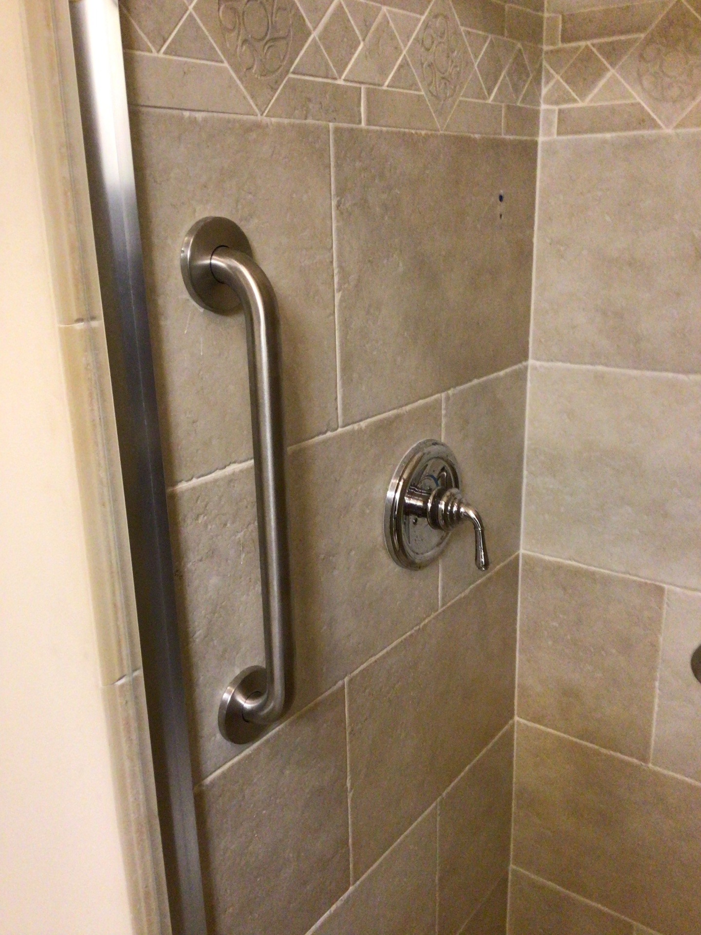 Vertical grab bar mounted on tiled shower wall