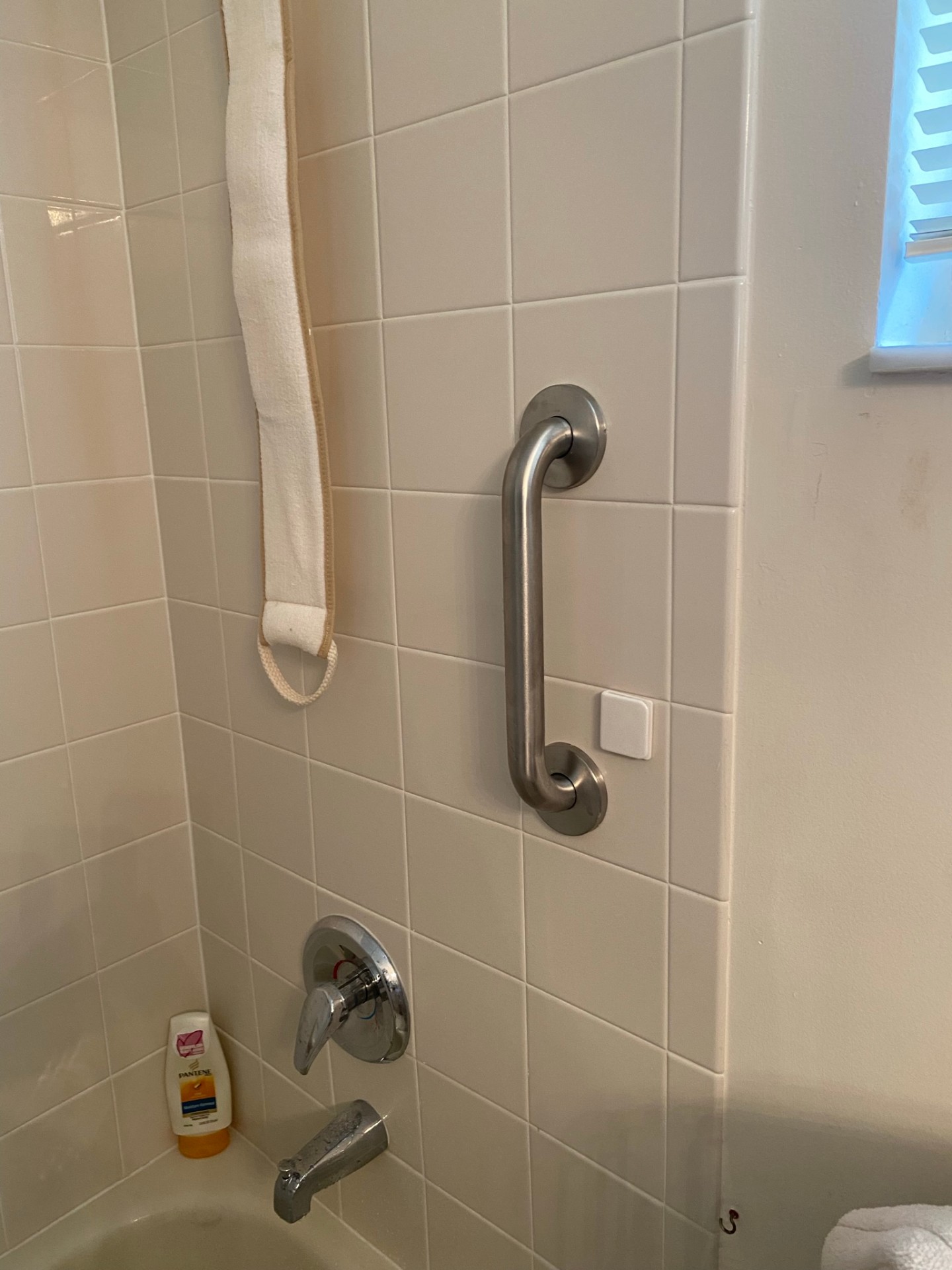 Compact grab bar on white tile next to bathtub